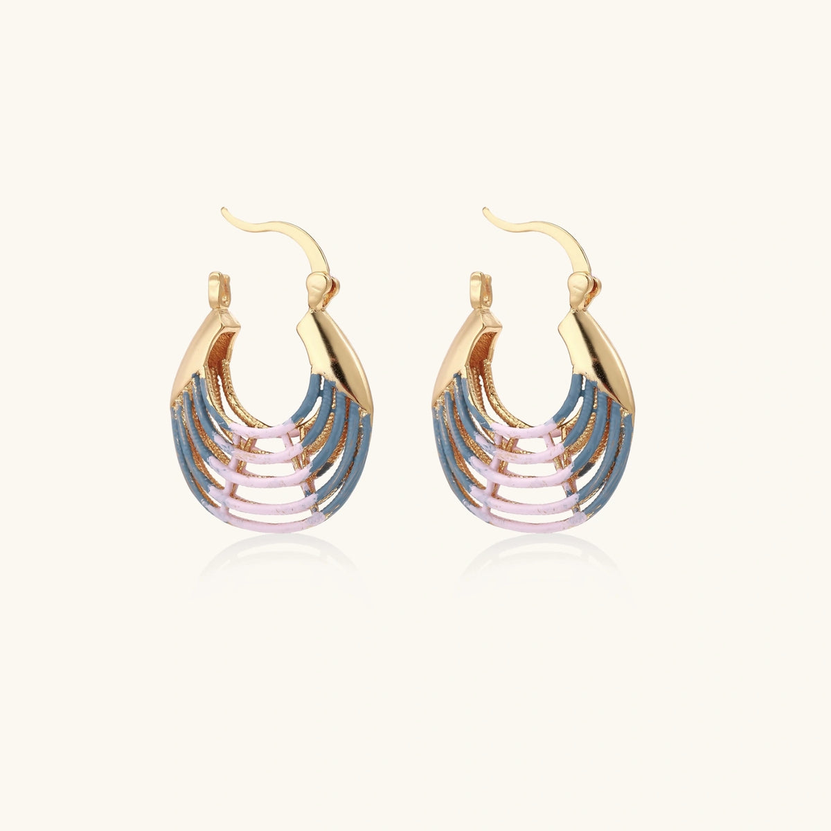 Gold hoop earrings with gradient blue-to-pink enamel in ribbed fan design on beige background